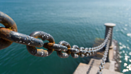 Close-up of a rusty metal chain anchor point with bubbles in blue water
