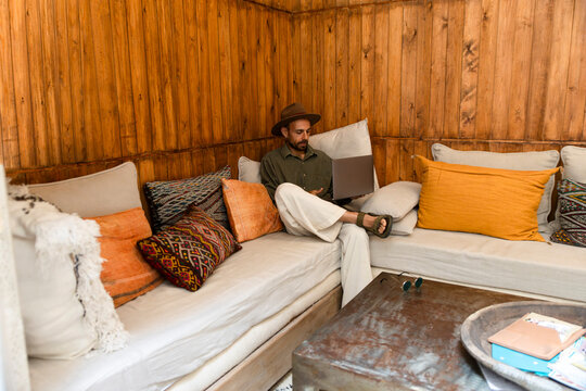 Digital nomad working remotely on laptop in wooden cozy common room