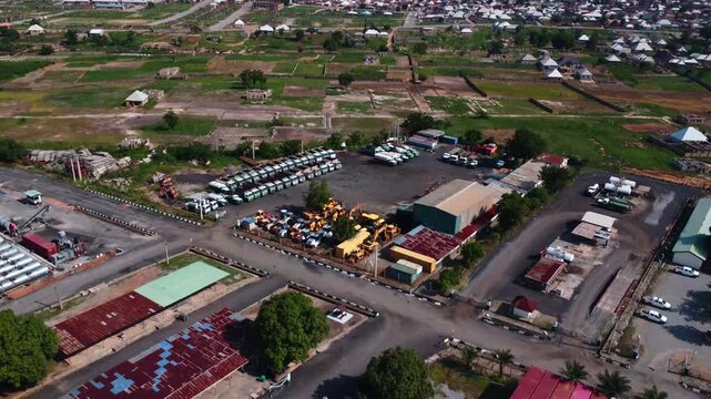 Aerial shot of construction yard with heavy equipment and Nigerian city beyond