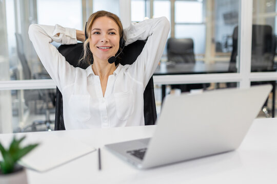 Young woman sitting in the office and stretching after a long working day - Powered by Adobe