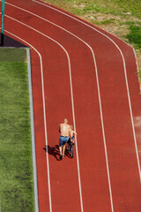 Father teaching his son to ride a bicycle on a running track. A touching moment of family bonding and learning, viewed from above. Childhood development and outdoor activity.