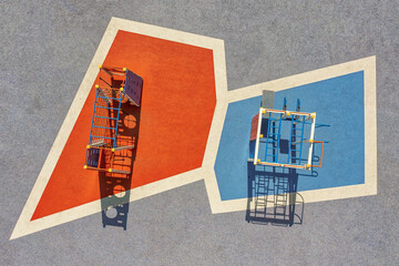 Aerial view of bold, contrasting geometric shapes in red and blue, framing playground structures in stark sunlight, Kharkiv, Kharkiv Oblast, Ukraine.