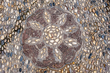 a cobblestone pavement featuring an intricate, symmetrical pattern with alternating dark and light stones forming a geometric design.