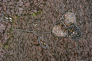 a cobblestone pavement featuring an intricate, symmetrical pattern with alternating dark and light stones forming a geometric design.