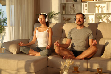 Couple of amateur yogis doing yoga at home listening online guide
