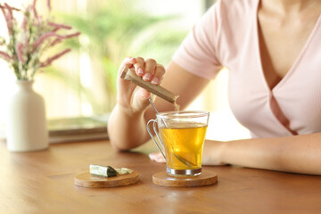 Woman hand pouring sugar in tea on a table at home