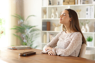 Woman breathing and smelling incense stick burning at home