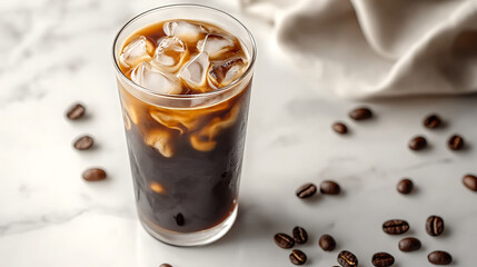 Tall glass of iced coffee with milk and ice cubes on marble surface, surrounded by scattered coffee beans, creating refreshing and inviting beverage scene