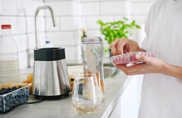 Little Girl Making A Milkshake Adding Raspberry To The Fruit Shake