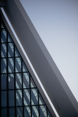 A low-angle, abstract shot of the modern, geometric facade of a building. The diagonal lines and...