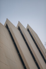 A modern building's facade with sharp, geometric peaks and a repeating window pattern, captured...