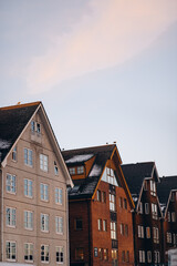 The gabled roofs of traditional buildings in Tromsø, Norway, stand out against a soft, pastel-colored evening sky, showcasing the city's charming and classic architecture.