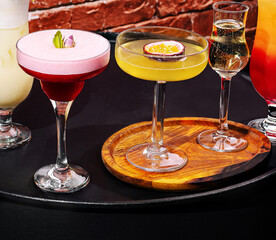 Colorful cocktails served on a wooden tray in a lively bar setting
