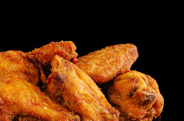Crispy fried chicken wings piled on a black surface perfect for snacking