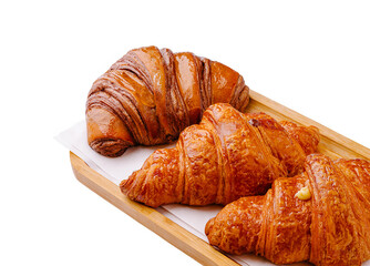 Freshly baked croissants arranged on a wooden tray with a warm glow