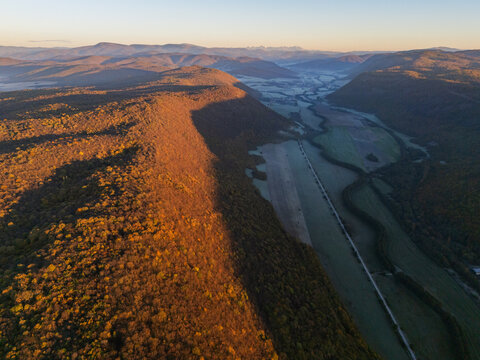 Aerial view of a valley with a river cutting through it, flanked by hills and forests bathed in the warm glow of the setting sun, Ple&Aring;&iexcl;ivec, Ko&Aring;&iexcl;ice Region, Slovakia.