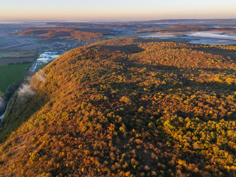 Aerial view of a landscape with golden light casting shadows across the dense forest, Ple&Aring;&iexcl;ivec nestled below, Ko&Aring;&iexcl;ice Region, Slovakia.