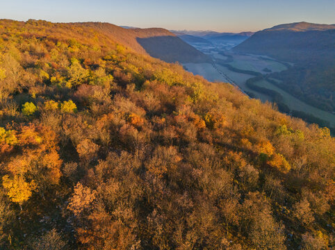 Aerial view of the rolling hills covered in autumn foliage with vibrant oranges and yellows contrasting against the greens, Ple&Aring;&iexcl;ivec, Ko&Aring;&iexcl;ice Region, Slovakia.