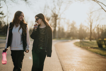Two teenage friends strolling outdoors in a park under the warm sunlight, enjoying each other's company and sharing a joyful and carefree moment