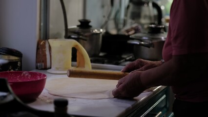 Wrinkled hands skillfully prepare dough on a floured surface, with kitchen utensils in the background. This moment captures the patience, love, and experience passed down through generations in home