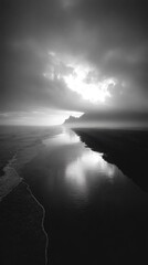 Monochromatic coastal scene, calm water reflecting cloudy sky