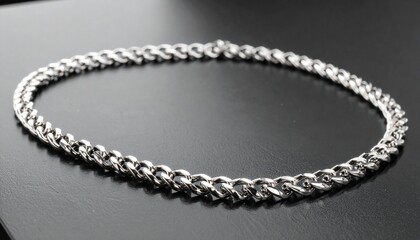 Fototapeta premium Bold silver chain necklace with thick interwoven links, displayed on a textured black surfaceBold silver chain necklace with thick interwoven links, displayed on a textured black surface