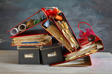 Messy file folders, ring binders grungy paperwork.Red tape, bureaucracy, overworked, beat the clock business concept on grungy  background.
