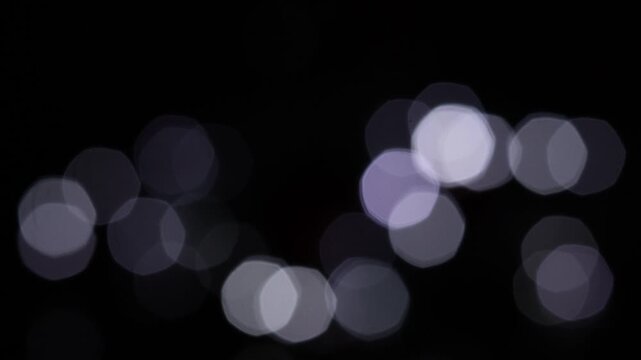 Una toma de cerca de luces de varios colores en forma de c&iacute;rculos en movimiento en la oscuridad. Desenfoque, efecto Bokeh. 