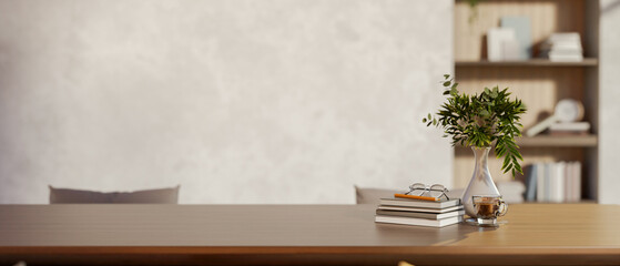 Glasses and pencil atop books aside vase on wooden table in a room with loft wall and build in shelf © bongkarn