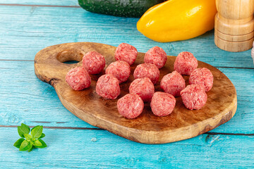 Raw beef meatballs over board