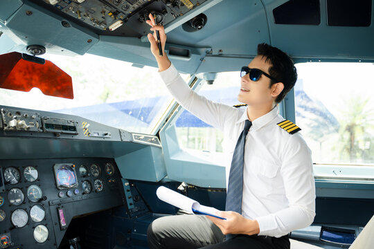 Professional airline pilot in uniform inspecting cockpit control panels during safety checks, ideal for aviation, travel, and airline safety themes.