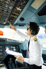 Professional airline pilot in uniform inspecting cockpit control panels during safety checks, ideal...