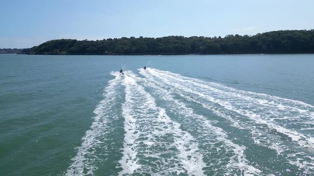 Torbay, South Devon, England: DRONE VIEWS: The drone follows two jet skiers heading across the bay towards Brixham. Torbay is a popular UK holiday resort for water sports enthusiasts.