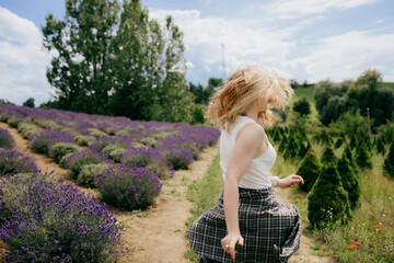 Blonde woman wearing white tank top and plaid shirt is twirling and running through rows of...