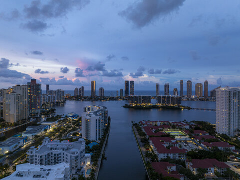 Aerial view of the Intracoastal Waterway reflecting the twilight sky between high-rise buildings and illuminated streets, Aventura, Florida, United States.