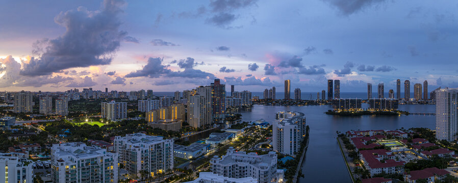 Aerial view of buildings and skyline ablaze with the fading light of dusk over the waters of Aventura, Florida, United States.