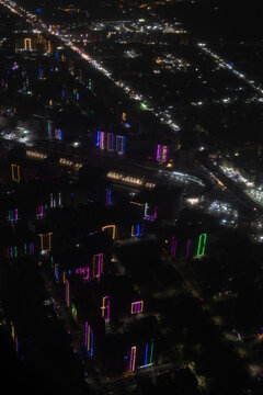 Aerial view of a cityscape ablaze with multicolored lights illuminating the urban fabric, creating a vibrant spectacle against the dark canvas of night, Cairo, Cairo Governorate, Egypt.