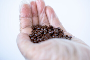 Cosmetic Hard wax beads for depilation, Female hand holding handful hard wax granules pellets,...