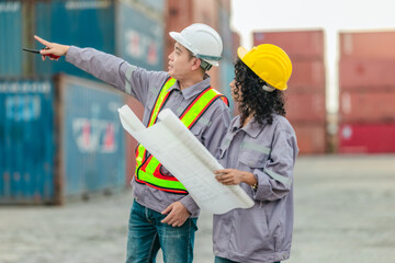 Industrial container workers discuss sustainable logistics operations. Analyzing blueprint,...