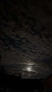 Moonlight illuminating dark cloudy night sky over mysterious landscape, dramatic nocturnal nature scene
