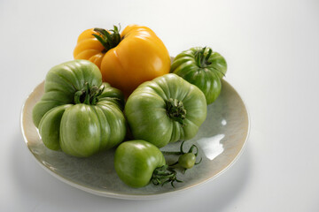 Colorful assorted heirloom tomatoes displayed on a ceramic plate against a light background