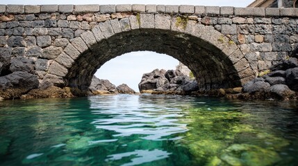 Traditional stone bridge spanning over turquoise sea waters on rocky shoreline