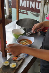 a hand is making a cheap street food spicy japanese ramen. Portrait or vertical mode, suitable for social media