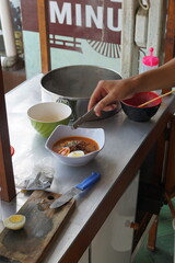 a hand is making a cheap street food spicy japanese ramen. Portrait or vertical mode, suitable for...