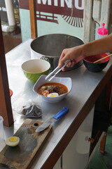 a hand is making a cheap street food spicy japanese ramen. Portrait or vertical mode, suitable for...