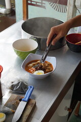 a hand is making a cheap street food spicy japanese ramen. Portrait or vertical mode, suitable for...