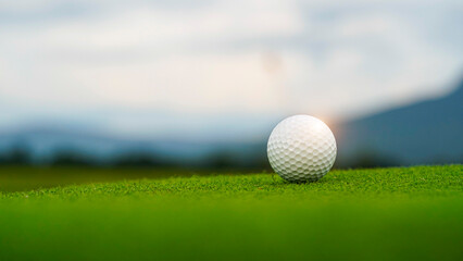Golf clubs and balls on a green lawn in a beautiful golf course with morning sunshine.