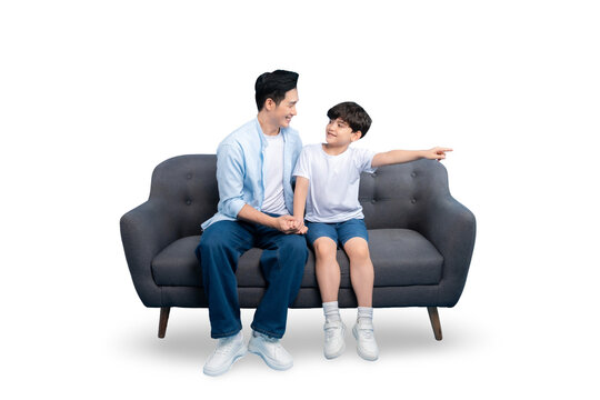 A father and son sharing a moment on the sofa, with the boy pointing with his hand on PNG background.