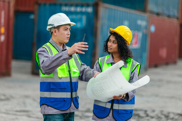 Industrial container workers discuss sustainable logistics operations. Analyzing blueprint, including zero emissions, reducing fuel consumption and carbon footprint in supply chain management