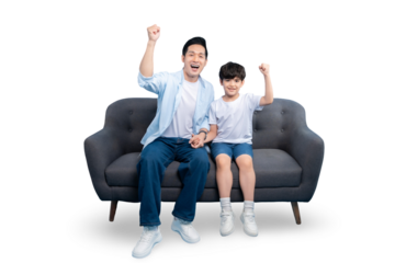 A Father and son are sitting on a sofa. The boy is raising his hand together , the son has a smile on his face. The background is white.